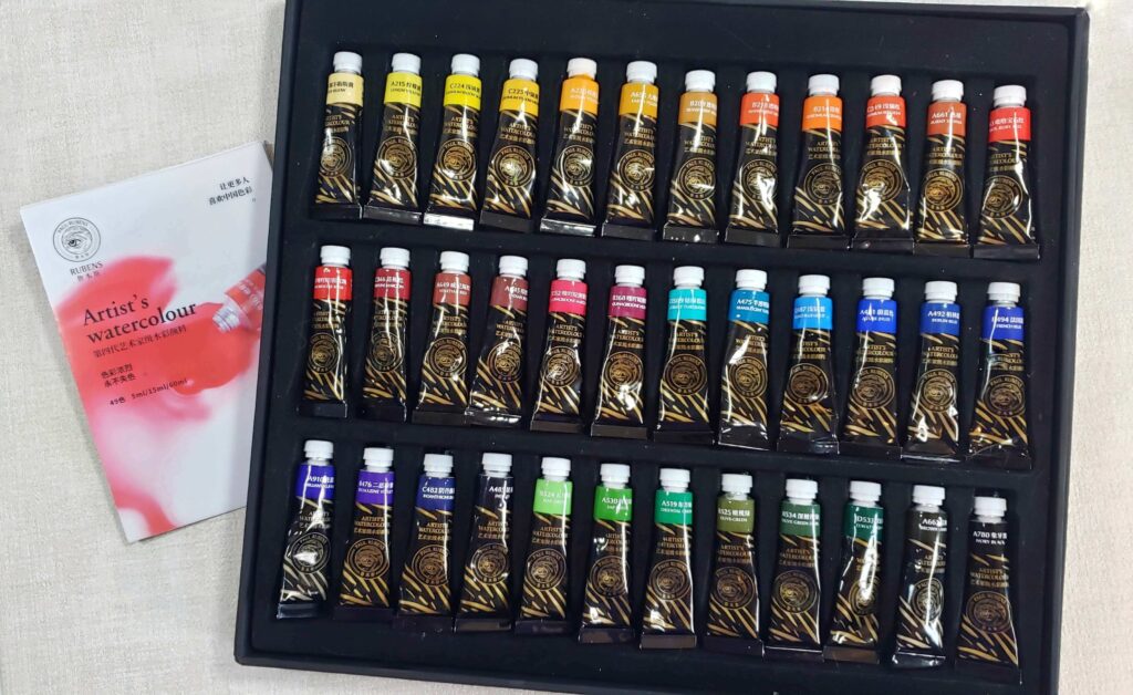 There is an image of the unboxed set of 4th generation watercolours by Paul Rubens. All 36 pigments are in tubes, and each tube is secured in it's allotted slot. There is a small booklet that comes with this set.