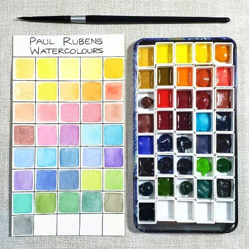 There is an image of the Paul Rubens 4th generation watercolors. All 36 pigments are swatched on the watercolor paper. Beside it is a tin with 36 pans in which each pigment has been squeezed.