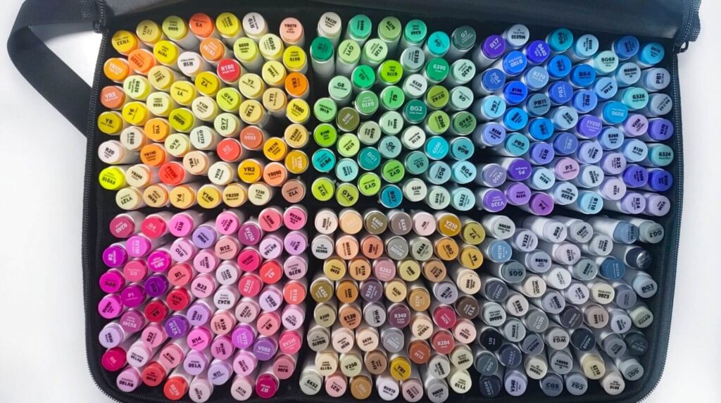 There is an image of a black carrying case that's filled with 320 Ohuhu Honolulu alcohol markers. The markers are divided into six colour groups: yellows/oranges, reds/pinks, blues/purples, greens, browns, and greys.